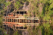 Camp exterior reflected on the water at Guma Lagoon Camp, Okavango Delta, Botswana